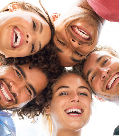 Five smiling children's faces arranged in a circle looking down at camera against white background.