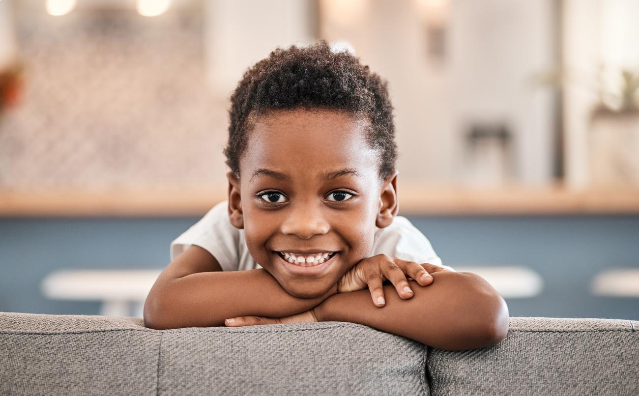 Young child smiling at dental office counter, appearing happy and comfortable in pediatric dentistry setting.