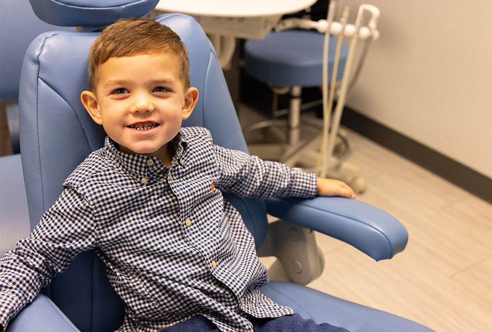 Young child smiling in dental chair at pediatric dental office.