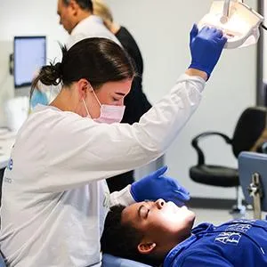 Pediatric dentist examining young patient's teeth in clinical dental office setting.