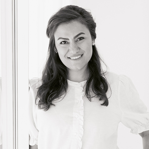 Professional headshot of a smiling woman in white shirt against neutral background.